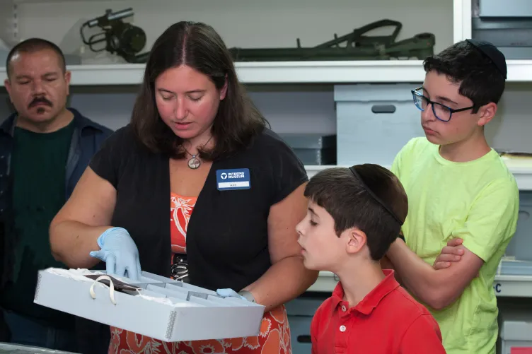 Visitors are looking at artifacts in a classroom.