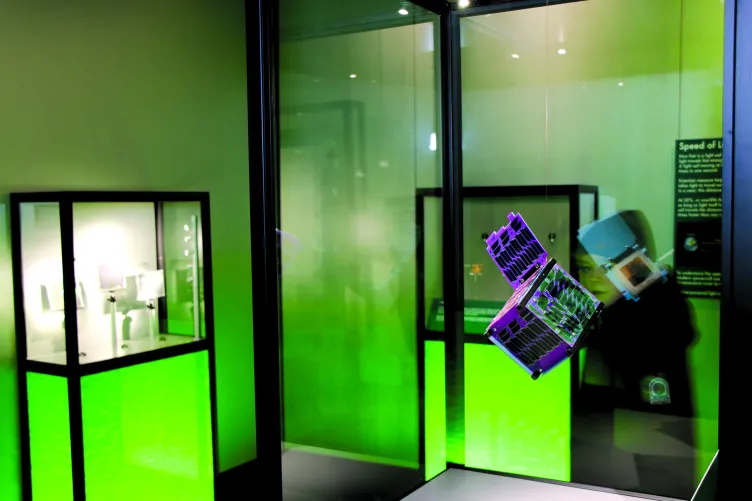 A holographic cube is suspended in mid-air in a display case.