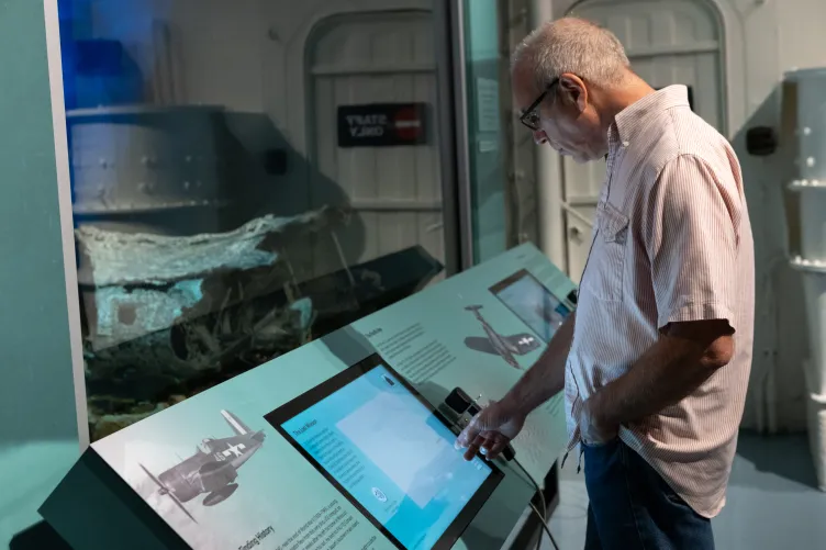 A museum visitor engaging with the Final Flight: The Story of a WWII Corsair exhibit.