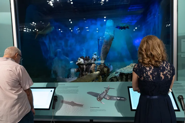 A museum visitors engaging with the Final Flight: The Story of a WWII Corsair exhibit.