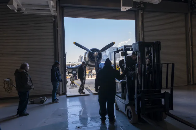 The restored Corsair being moved by Intrepid Museum employees from the Aircraft Restoration Hangar to the new exhibition space in Hangar 1. 