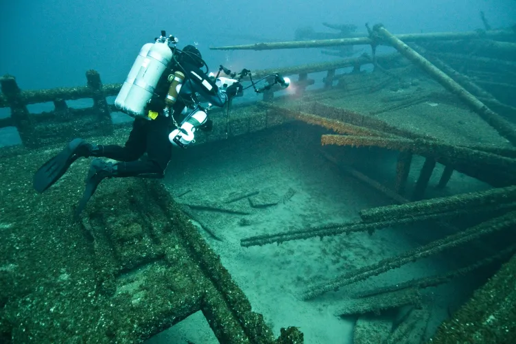 A technical diver illuminates below decks at the site of John J. Audubon