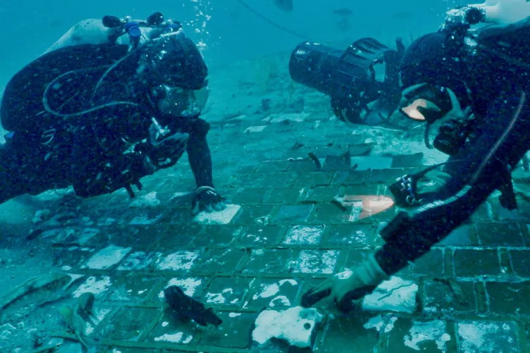 2 divers examining tiles on the ocean floor