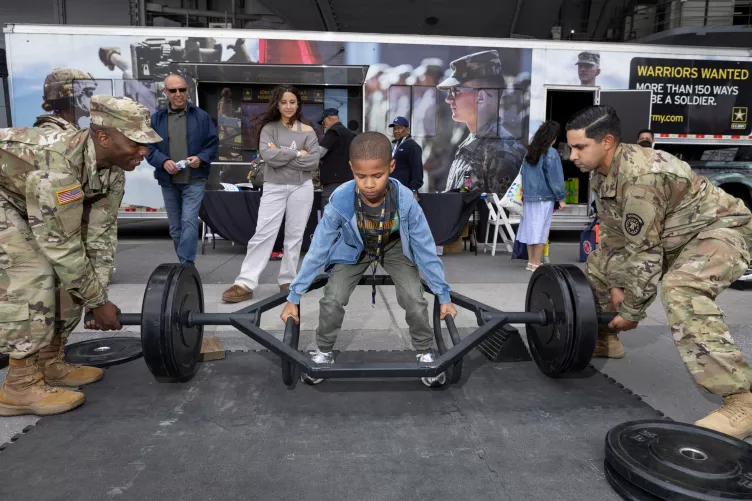 Visitors trying on U.S. Army gear and lifting weights during Fleet Week.