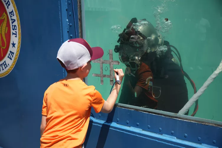 Child drawing on an army water tank during fleet week 