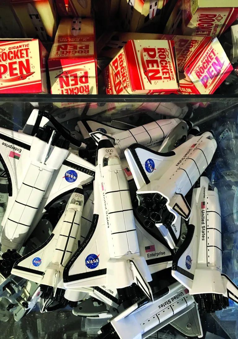 Space shuttle toys and rocket pens available for purchase at the shop.