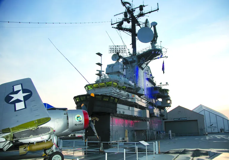 Intrepid’s island rises high above an aircraft parked on the ship's flight deck