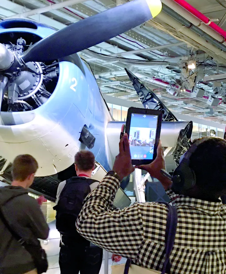 A visitor with a headset and iPad looking at an airplane