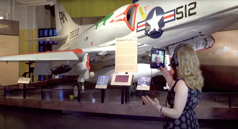 Visitors using wheelchairs are seated and looking at the LEGO Intrepid