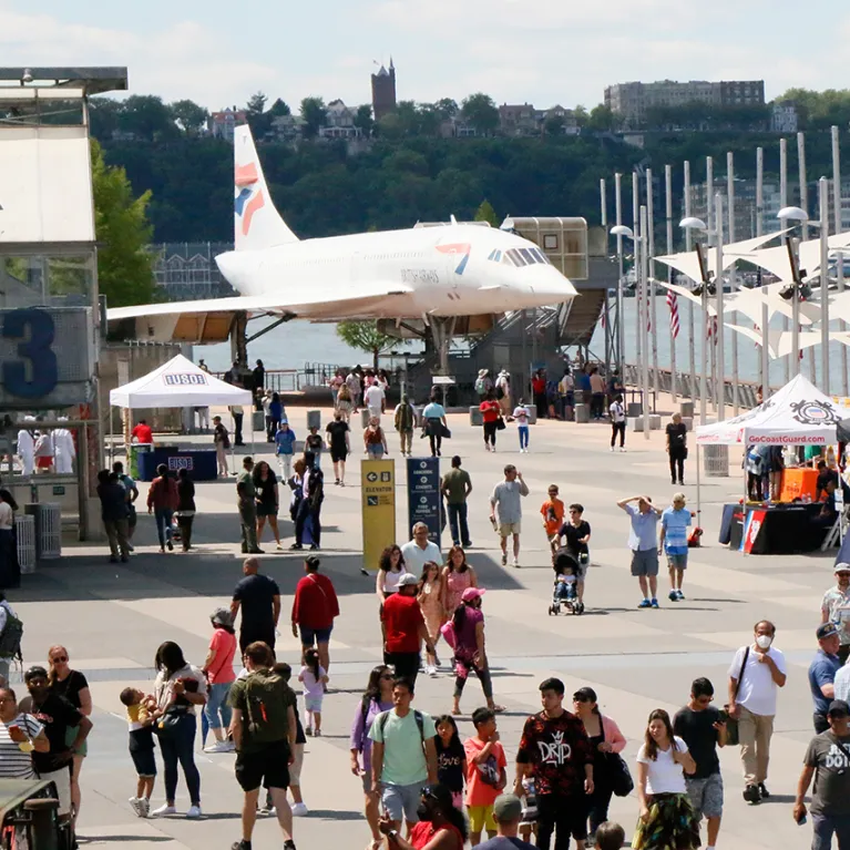 Museum visitors are walking around on Pier 86 and the British Airways Concorde is in the background.
