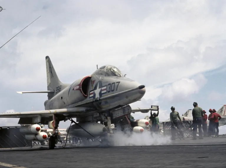 An archival photo of people on the flight deck with a plane.