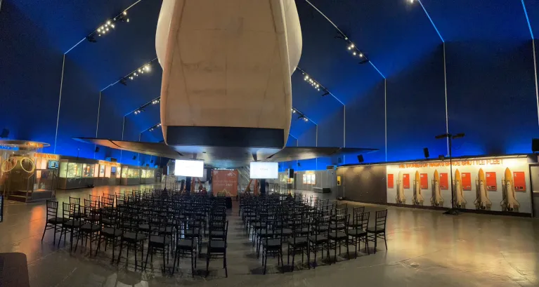 Theater style seating in the Space Shuttle Pavilion facing two tall monitor screens