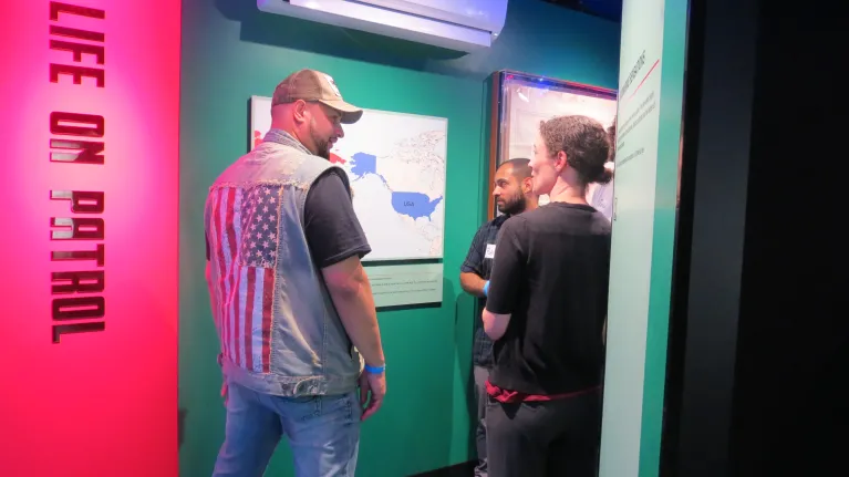 Museum curator guiding veterans through an exhibition after hours.