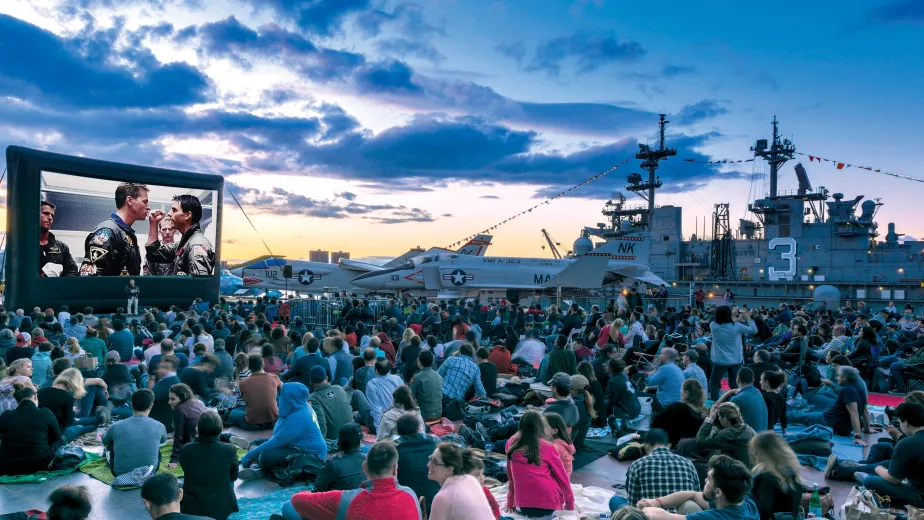 Movie Night Crowd at the Flight Deck during sunset, large movie screen, and Aircraft in the background 