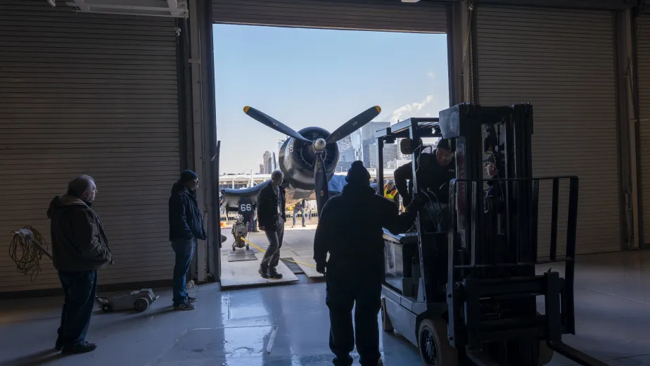 The restored Corsair being moved by Intrepid Museum employees from the Aircraft Restoration Hangar to the new exhibition space in Hangar 1. 