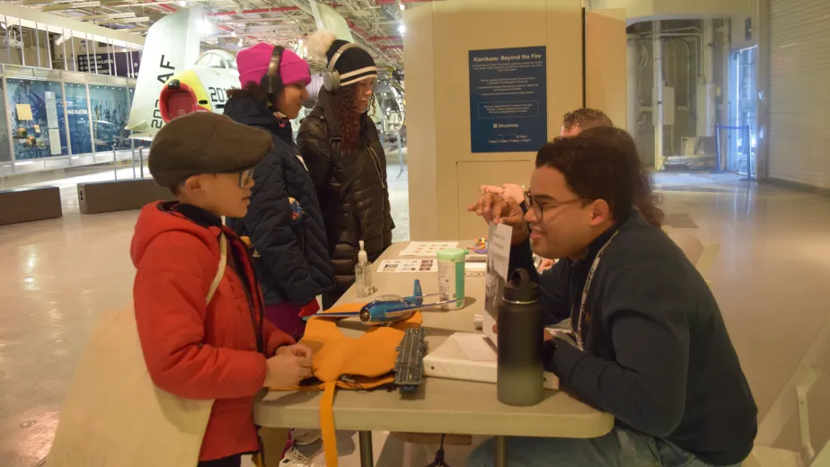 An educator engages with families during an activity at the Intrepid Museum.