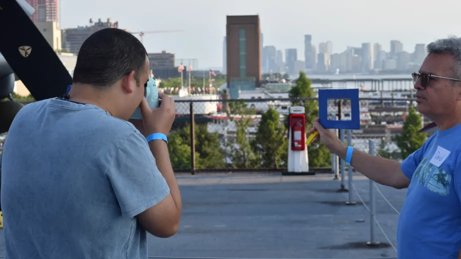 A young man takes a photo of a rectangular frame held by another man