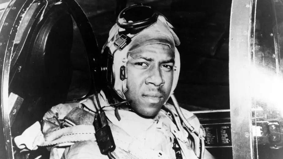 Jesse Brown in his flight suit and aviator helmet in the cockpit of an F4U Corsair.